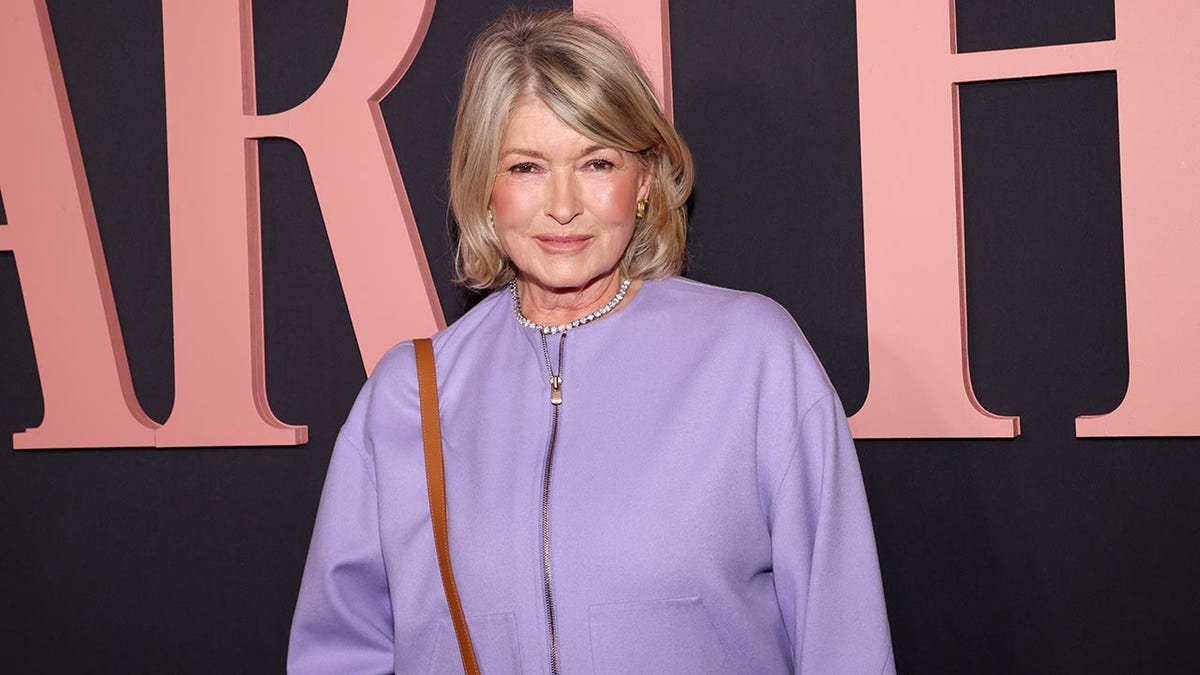 Martha Stewart in a lavender jacket smiles softly on the carpet as she watches her first movie